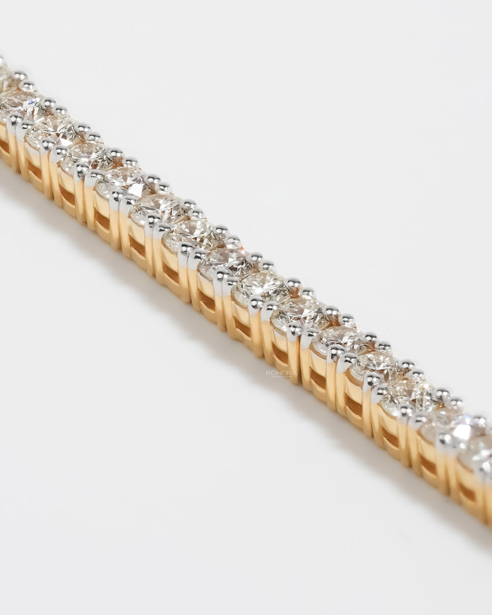 Close-up of round lab grown diamond tennis bracelet stones in prong settings on a yellow gold frame