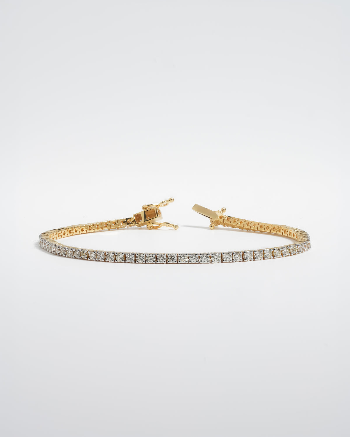 Round lab grown diamond tennis bracelet in yellow gold with the box clasp open, front view on a white background