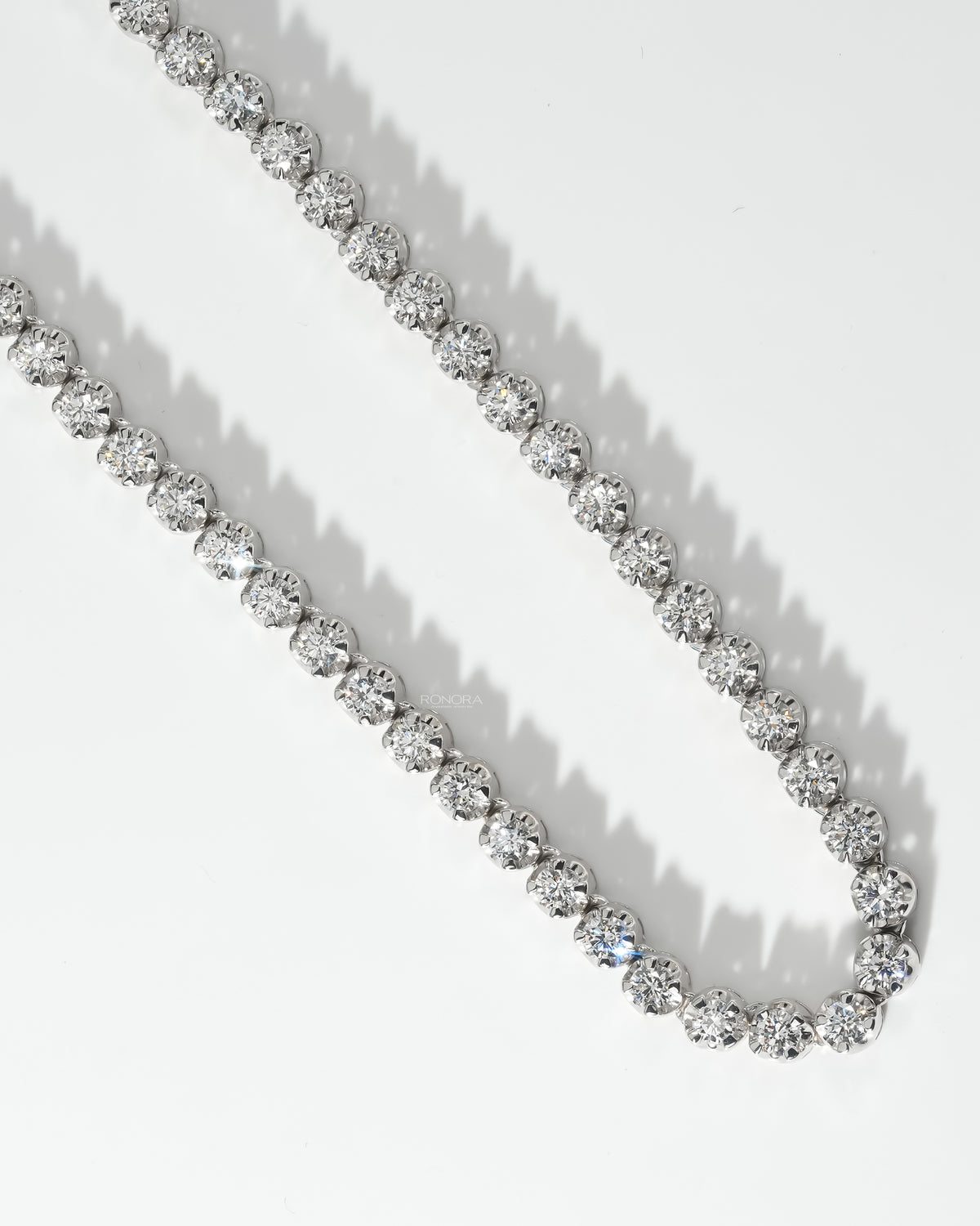 Close-up of bright round stones on a lab grown diamond tennis necklace with polished white gold prongs