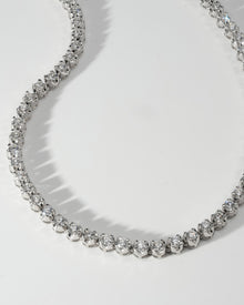 Close-up of a round prong set lab grown diamond tennis necklace in white gold on a white surface