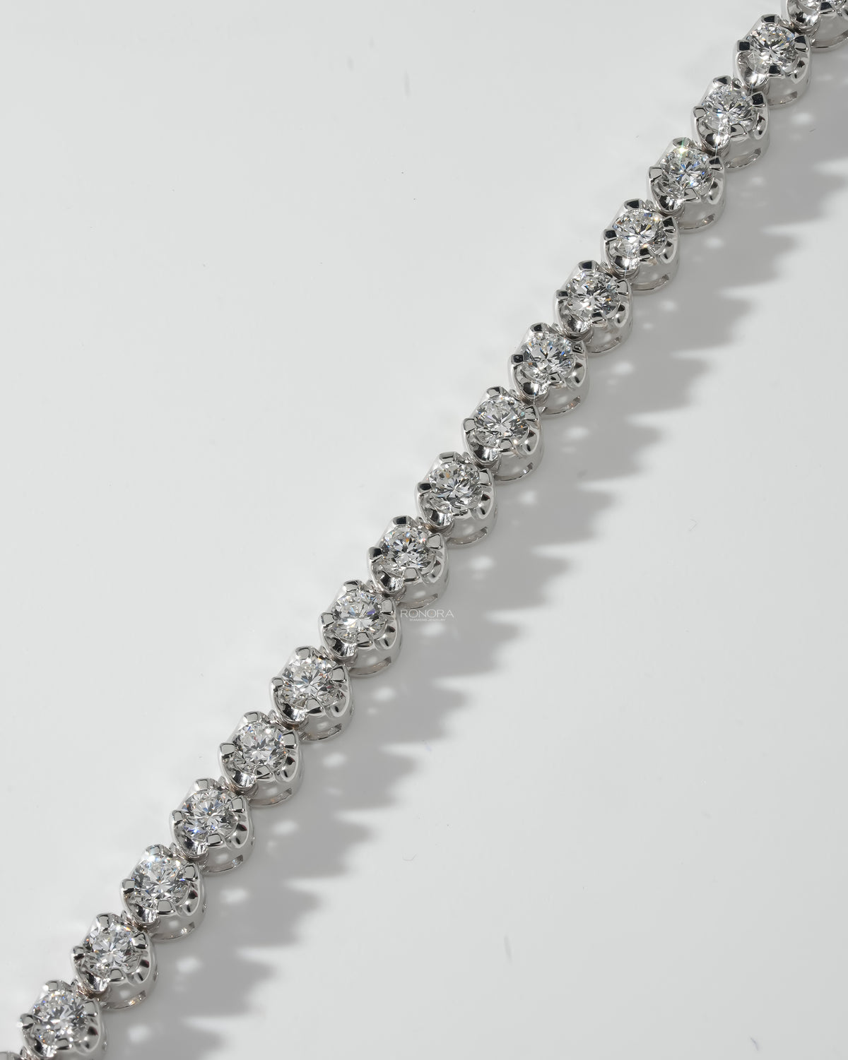 Detail of round prong set stones along a white gold lab grown diamond tennis necklace
