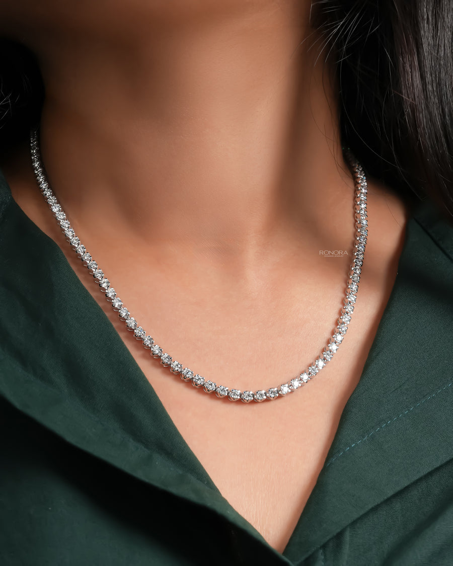 Woman wearing a round lab grown diamond tennis necklace in white gold with a dark green shirt