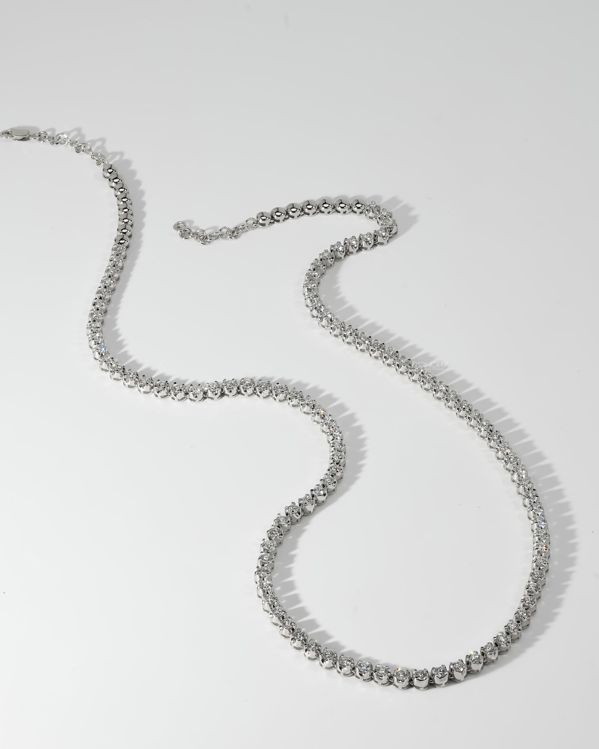 Full 10 carat lab grown diamond tennis necklace in white gold laid flat, showing stones and clasp