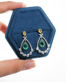Pair of lab grown emerald pear drop earrings with yellow pear tops in a blue velvet hexagon jewelry box