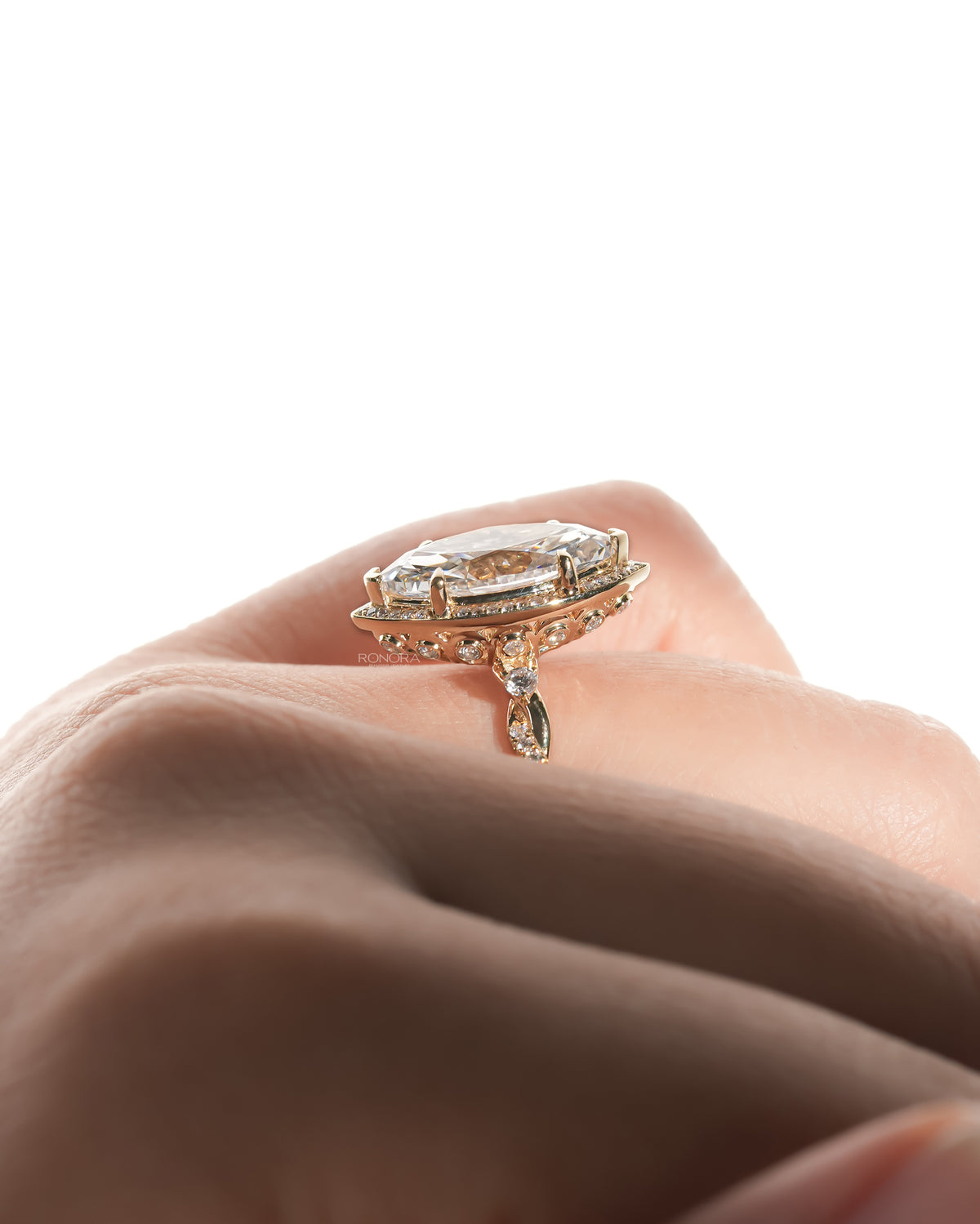 Side view of a marquise halo lab grown diamond ring in gold on a finger, showing the pave halo and filigree gallery
