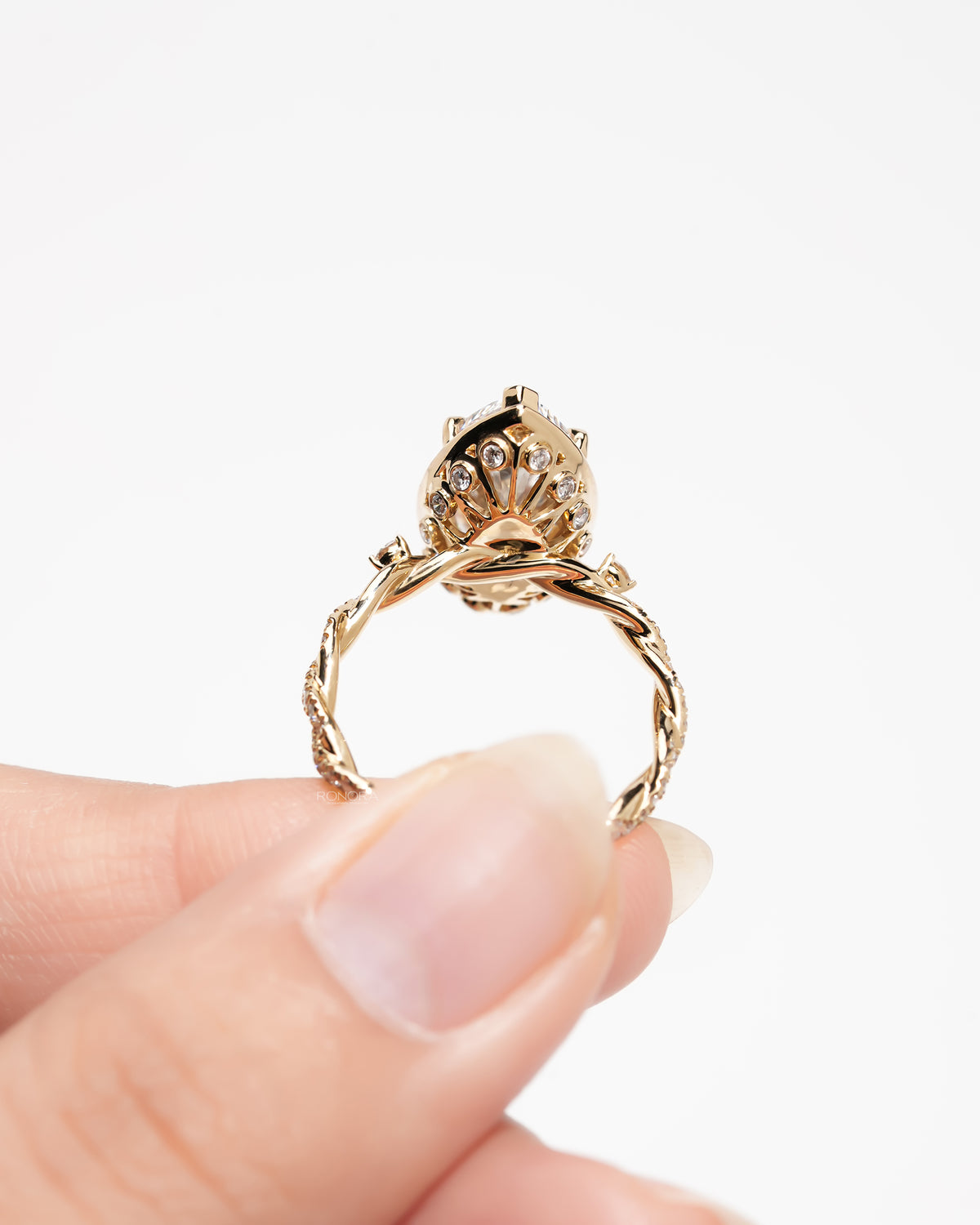 Back view of a marquise halo lab grown diamond ring in yellow gold showing the twist band and bezel gallery details