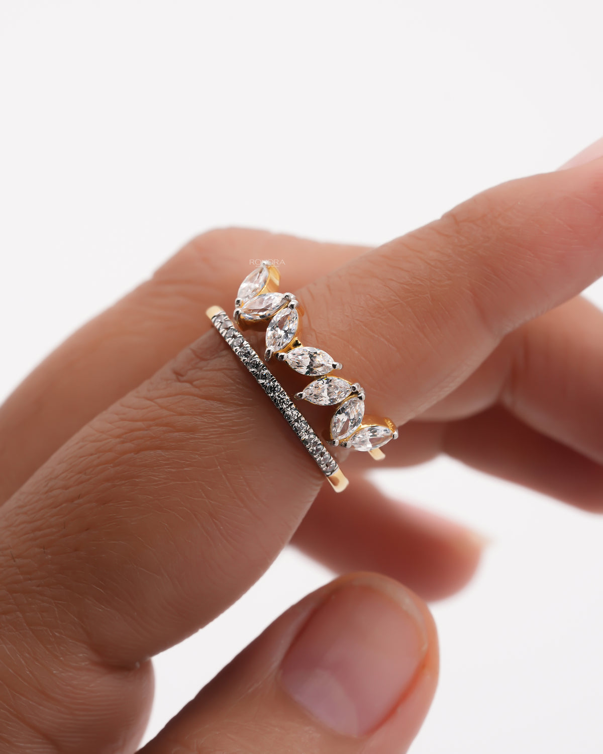 Close-up of a marquise lab grown diamond leaf wrap ring on a finger with a pave band running beside the marquise stones