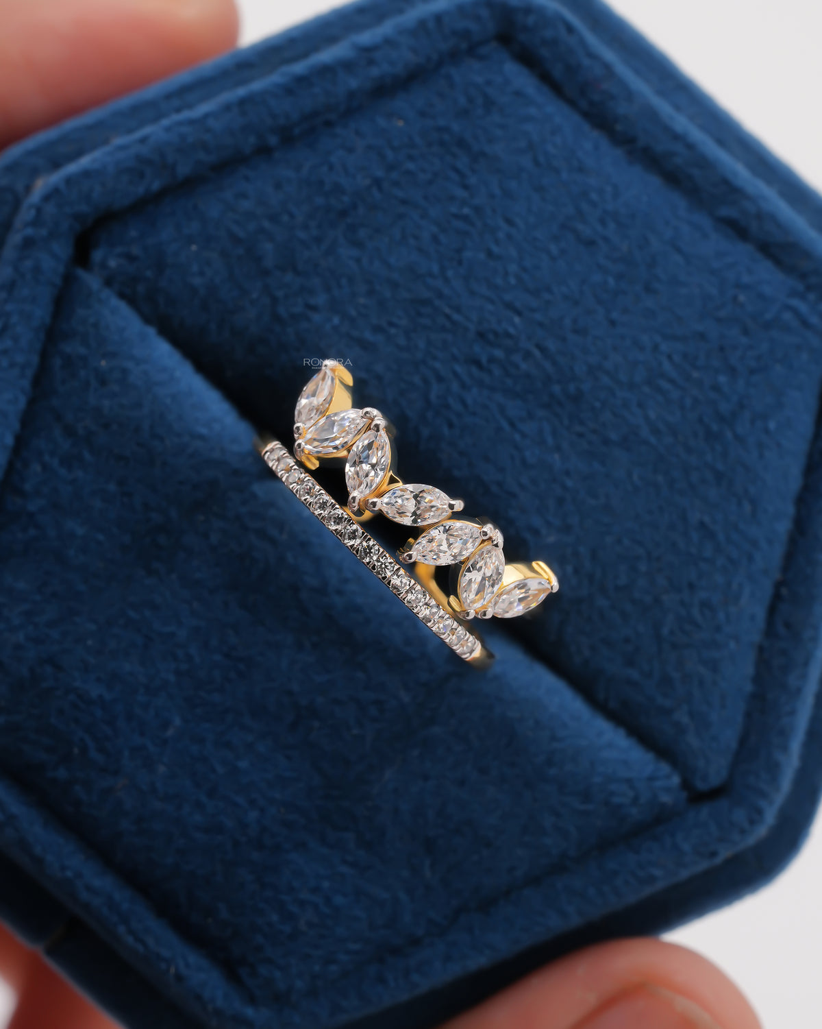 Top view of a marquise lab grown diamond leaf wrap ring in yellow gold with a pave band in a blue velvet box