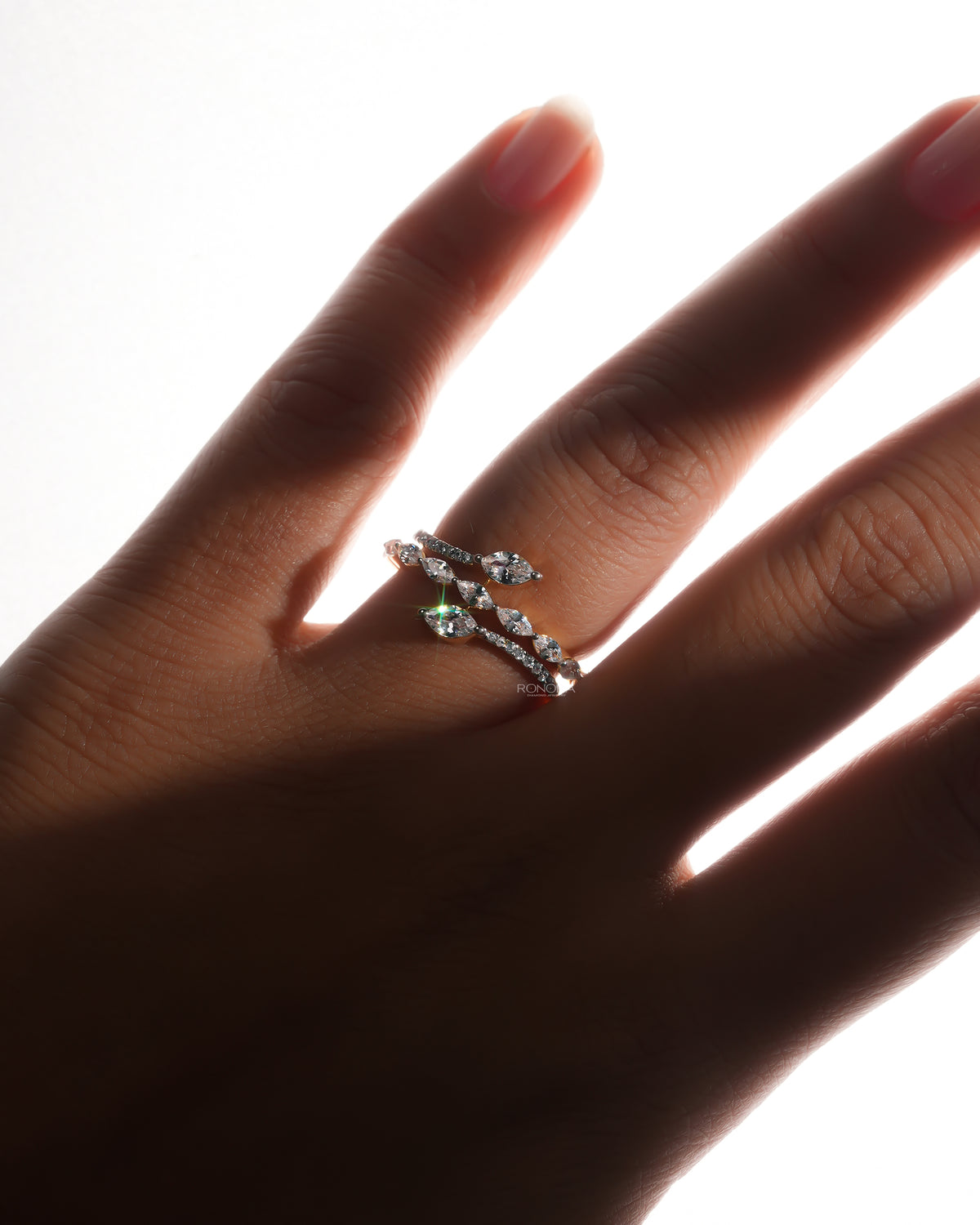 Marquise lab grown diamond vine ring with a snake wrap design worn on a backlit hand, stones catching the light