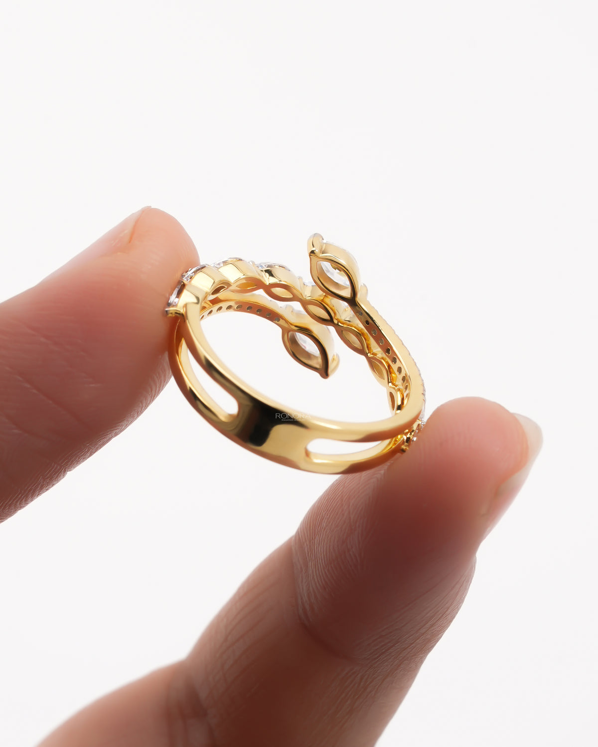 Back view of a yellow gold marquise lab grown diamond vine ring showing the open snake wrap band, held in fingers