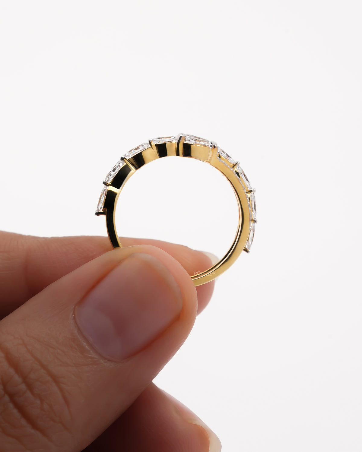 Side view of a yellow gold marquise lab grown diamond vine ring held between two fingers