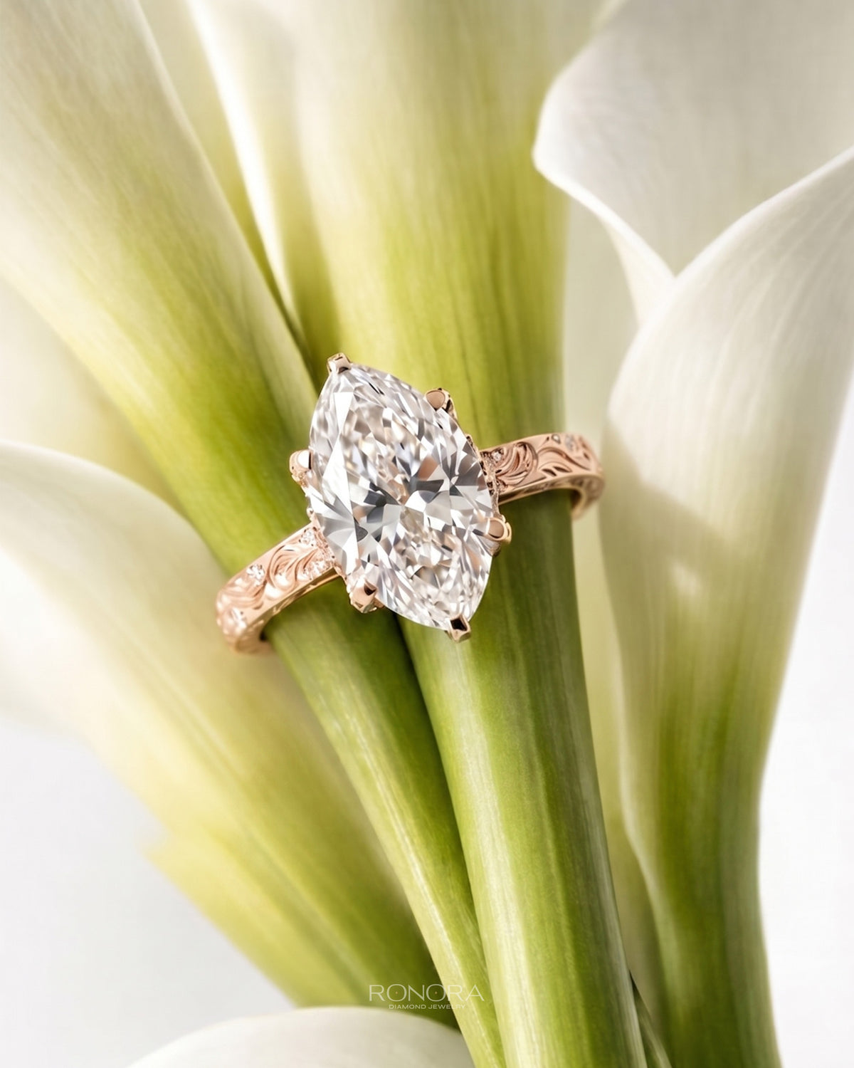 Marquise lab grown diamond vintage ring in rose gold with engraved band, resting on white calla lily stems
