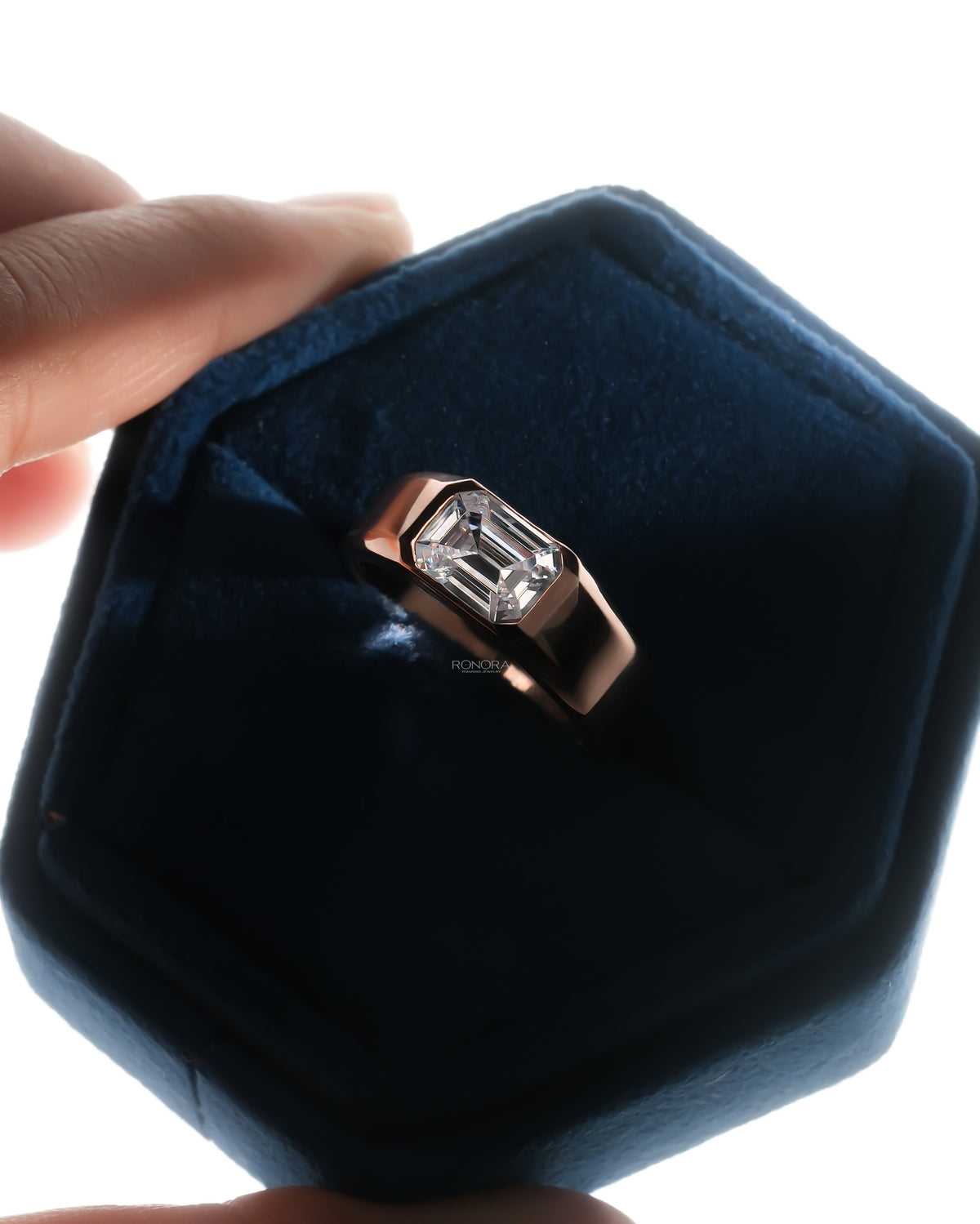 Men's emerald cut lab grown diamond ring in rose gold with a flush bezel setting, in an open navy velvet ring box