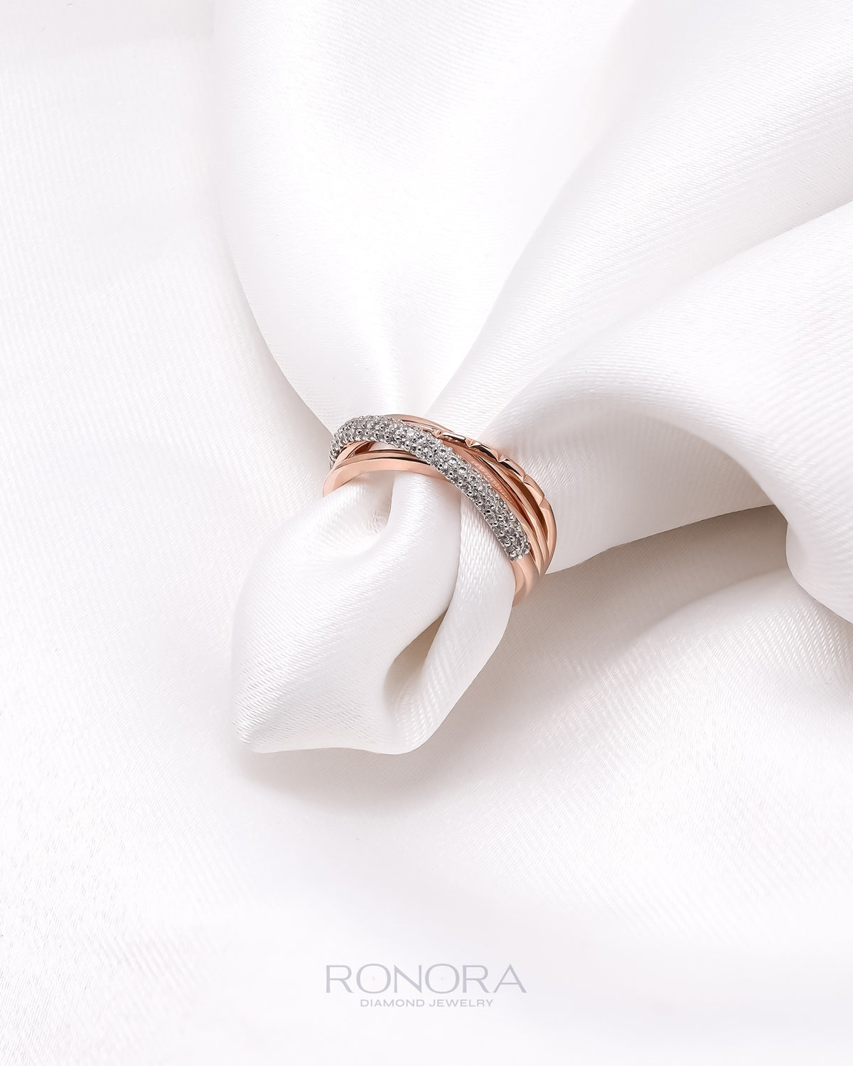 Multi row pave lab grown diamond band in rose gold with crossing stone rows, styled in folded white satin