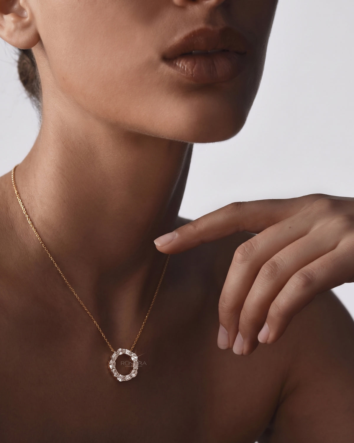 Model wearing an open circle lab grown diamond pendant necklace with oval and emerald cut stones