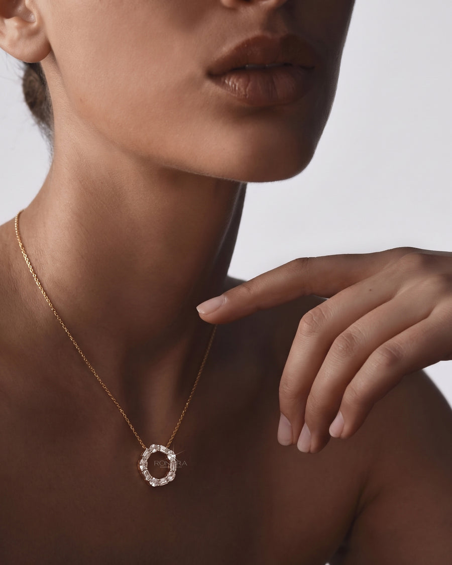 Model wearing an open circle lab grown diamond pendant necklace with oval and emerald cut stones