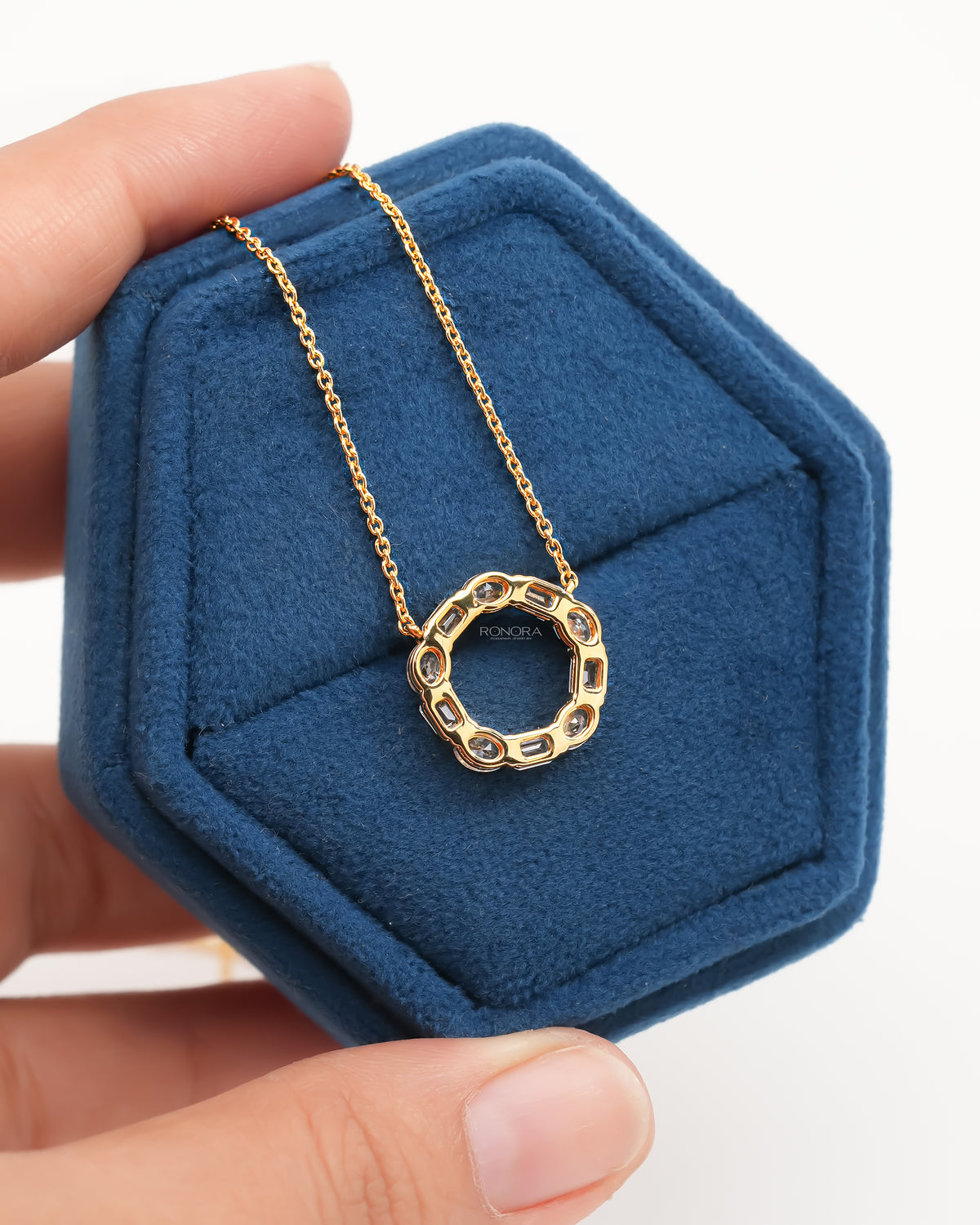 Back view of an open circle lab grown diamond pendant on a yellow gold chain in a blue velvet box