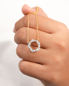 Open circle lab grown diamond pendant necklace with oval and emerald cut stones hanging over a hand