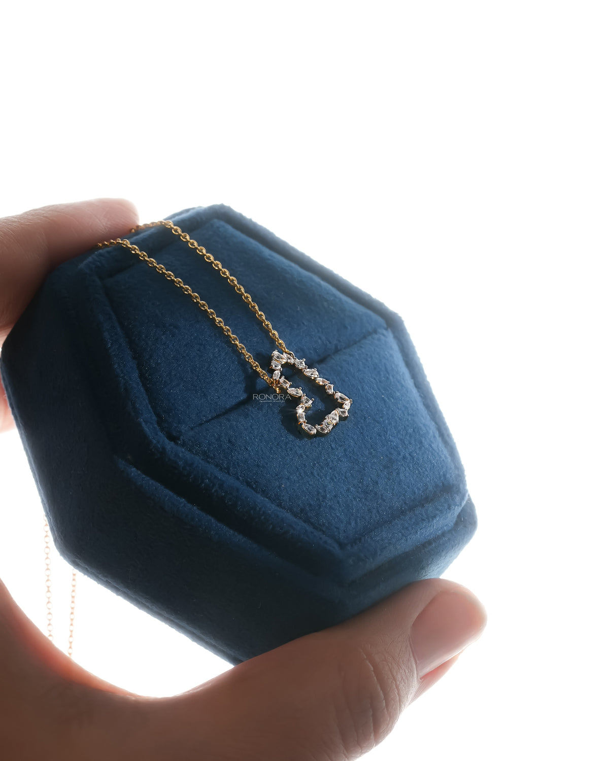 Angled view of an open heart lab grown diamond pendant necklace resting in a blue velvet jewelry box