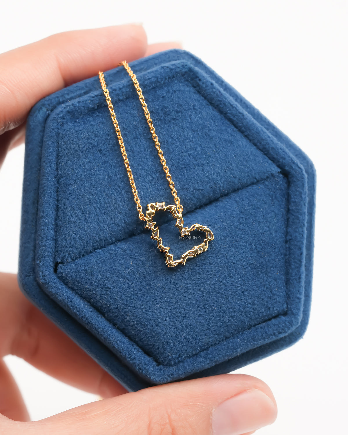 Back view of an open heart lab grown diamond pendant on a yellow gold chain in a blue velvet box