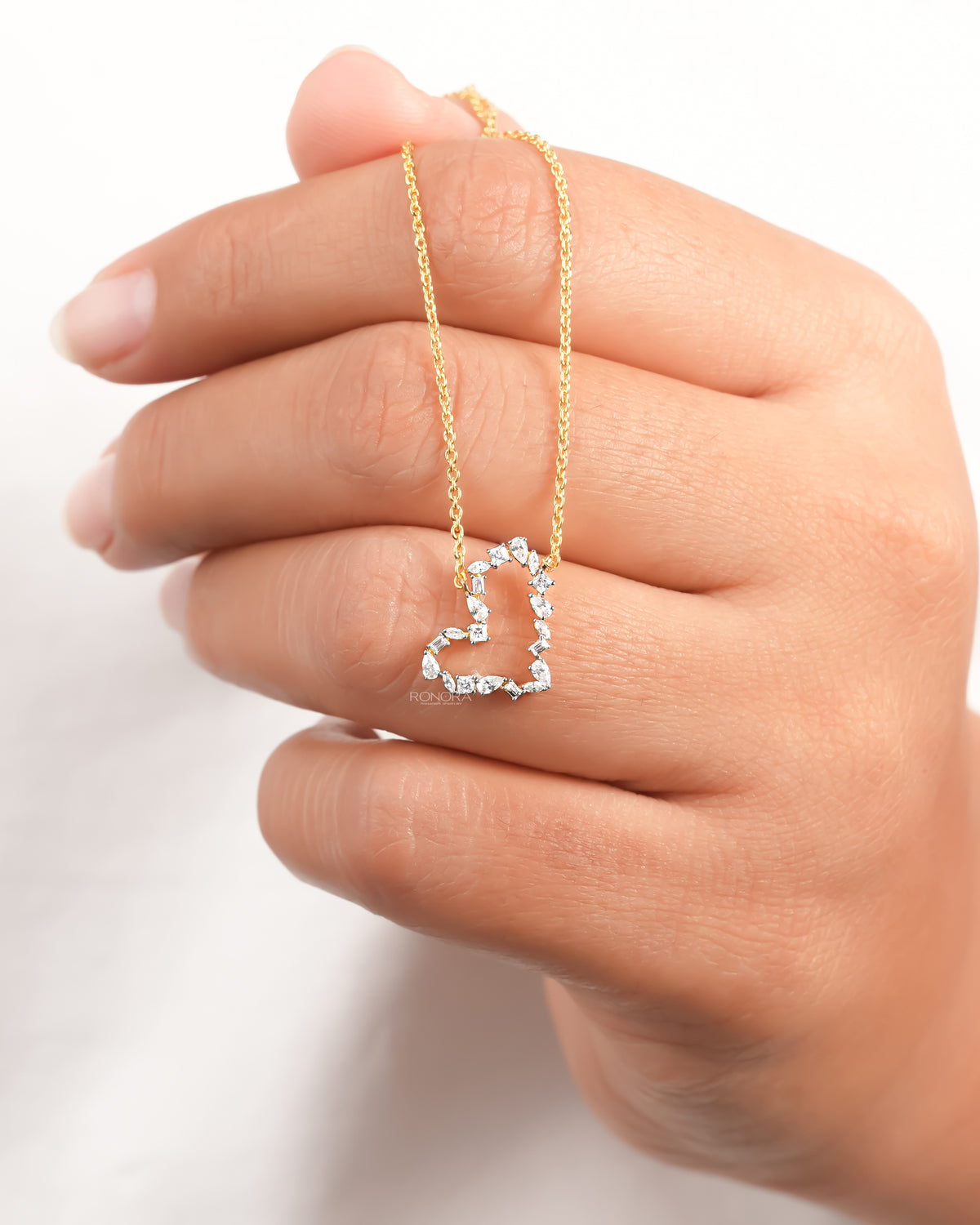Open heart lab grown diamond pendant necklace with mixed shape stones hanging over a hand
