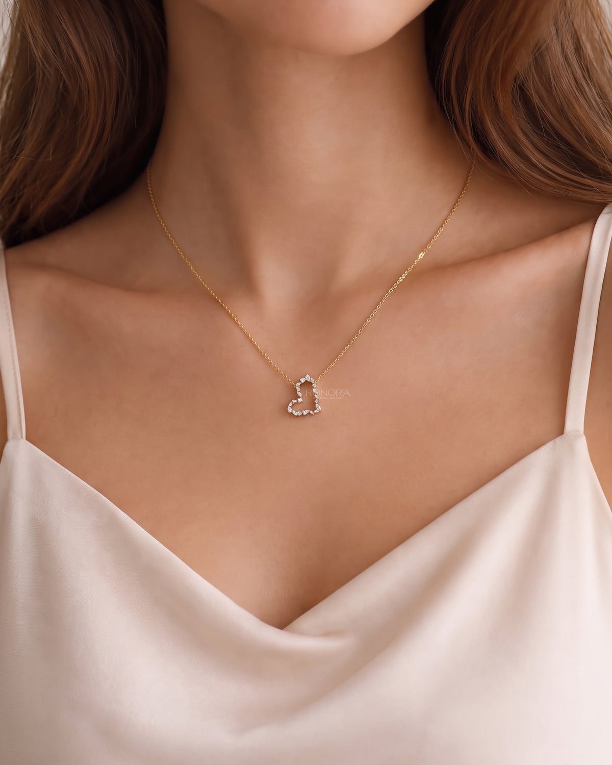 Model wearing an open heart lab grown diamond pendant necklace with mixed shape stones on a gold chain