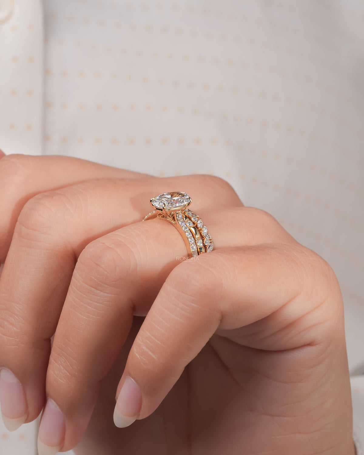 Oval lab grown diamond bridal set in yellow gold worn on a finger, side angle of the solitaire and two bands