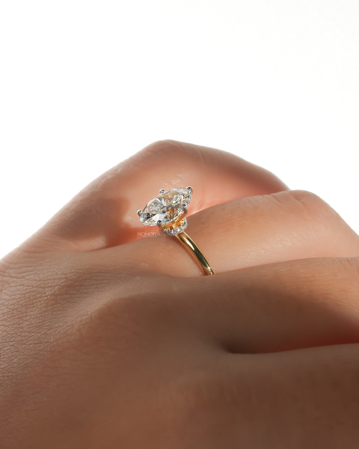 Oval lab grown diamond hidden halo ring in yellow gold worn on a finger, side angle showing the hidden halo
