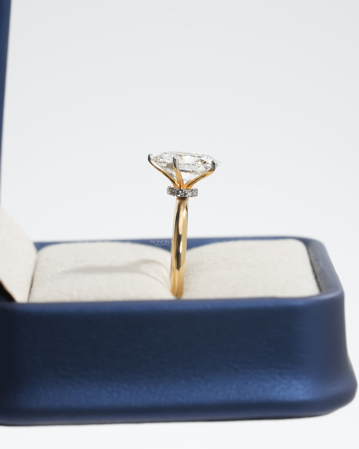 Side view of an oval lab grown diamond hidden halo ring in yellow gold showing the diamond halo under the stone