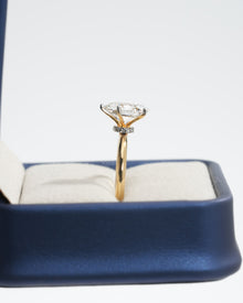 Side view of an oval lab grown diamond hidden halo ring in yellow gold showing the diamond halo under the stone