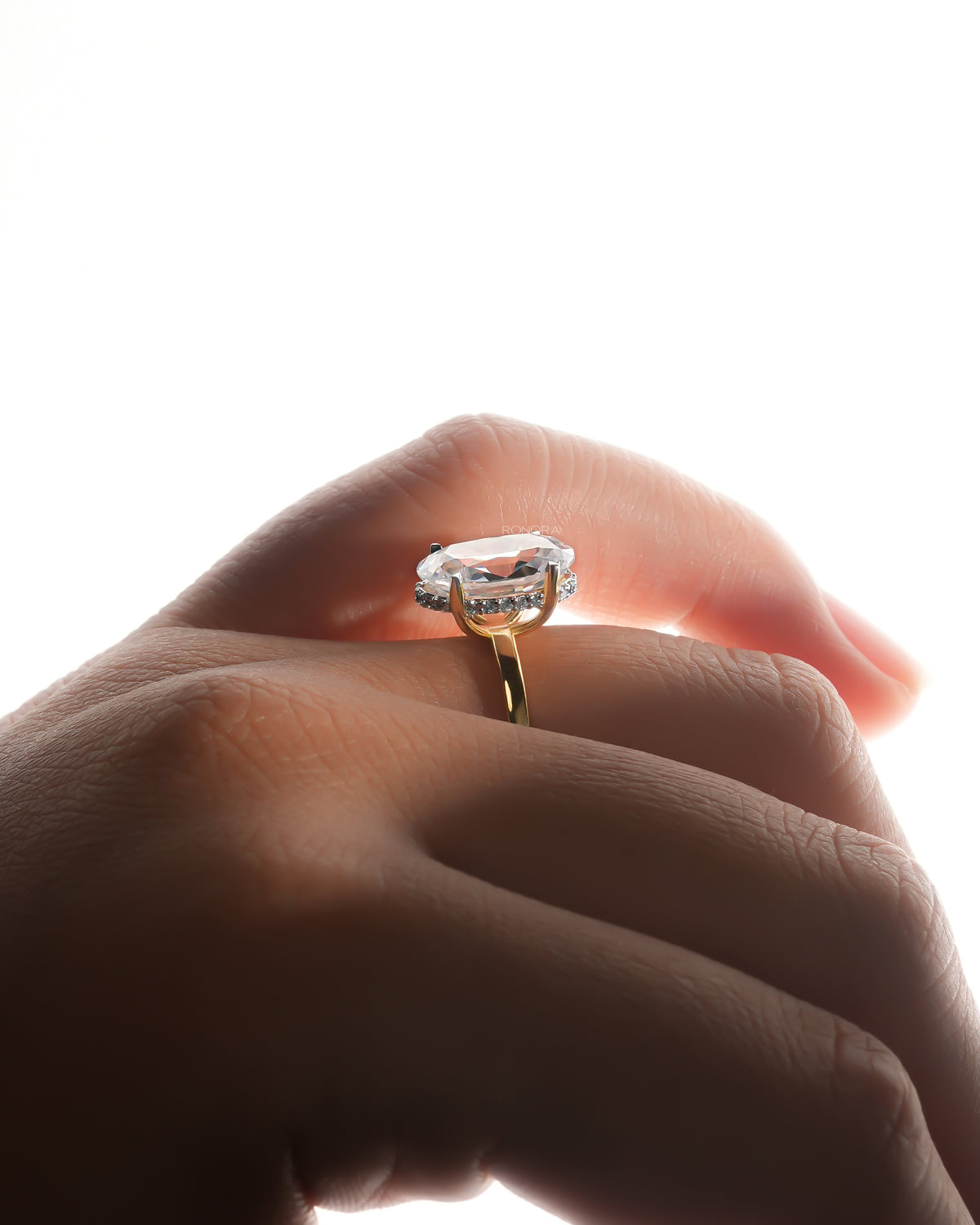 Side view of an oval moissanite hidden halo ring worn on a finger, showing the small stones hidden under the oval stone