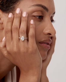 Woman with hands against her face wearing an oval lab grown diamond ring with a rose gold twisted pave band