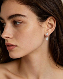 Woman in profile wearing pear lab grown diamond ear jacket earrings with one pear diamond on the lobe and one below
