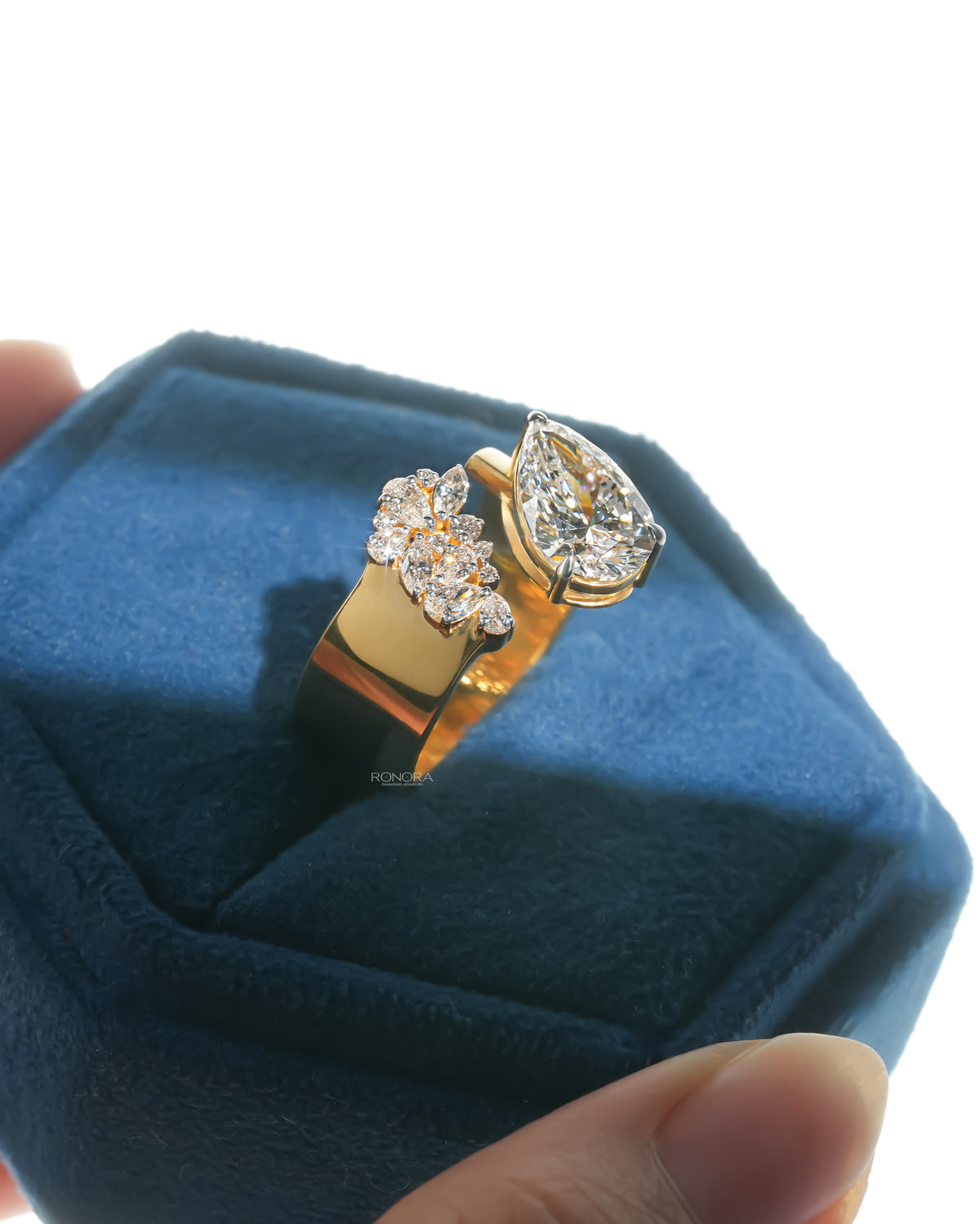 Angled view of a pear toi et moi lab grown diamond ring in yellow gold in a blue velvet ring box