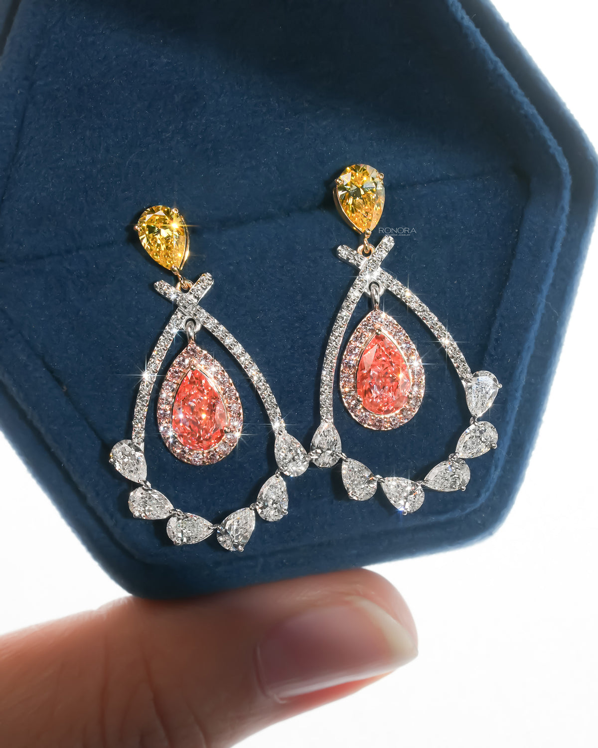 Pair of pink pear lab grown diamond drop earrings with yellow pear tops in a blue velvet hexagon jewelry box