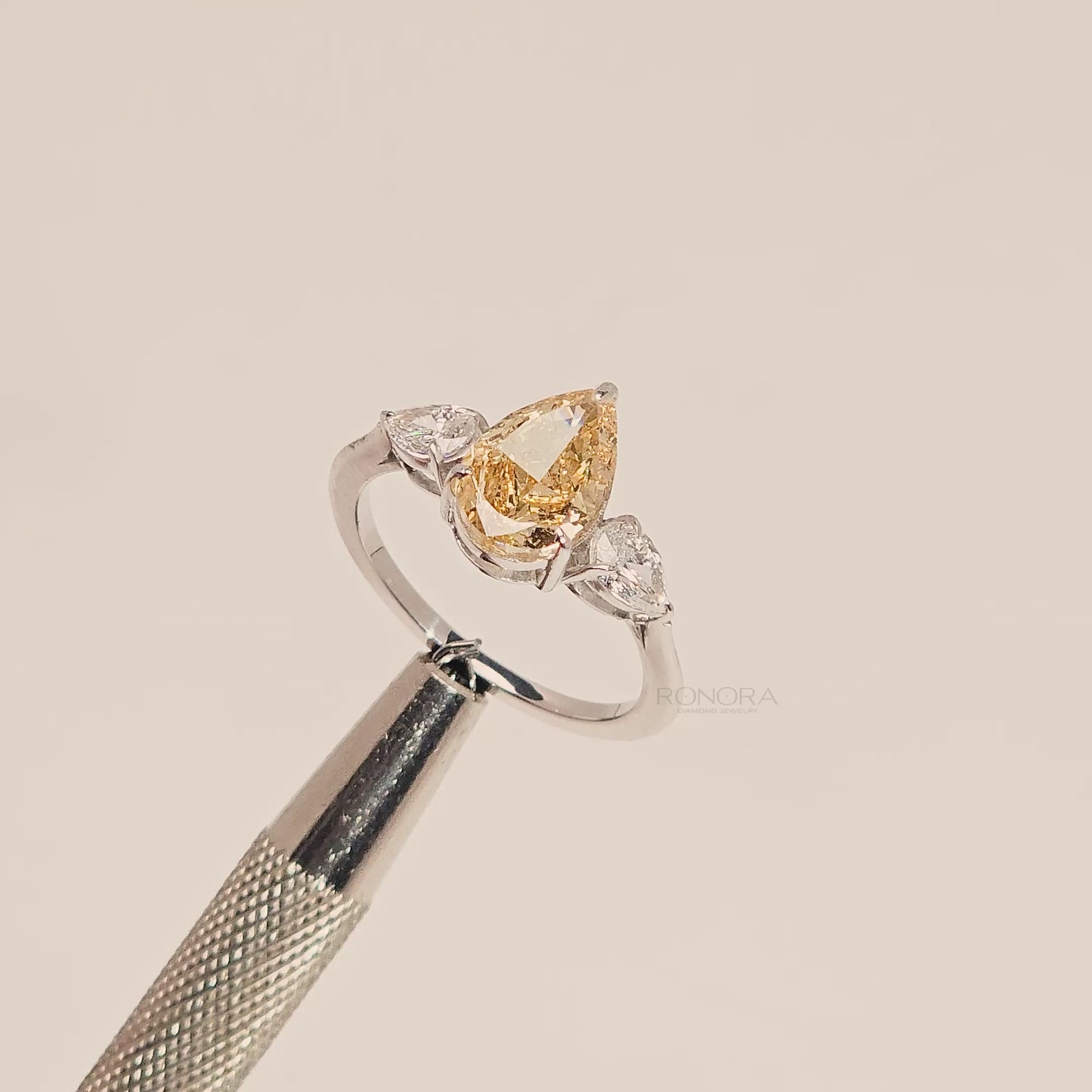 Close-up video of yellow pear lab grown diamond three-stone ring in white metal