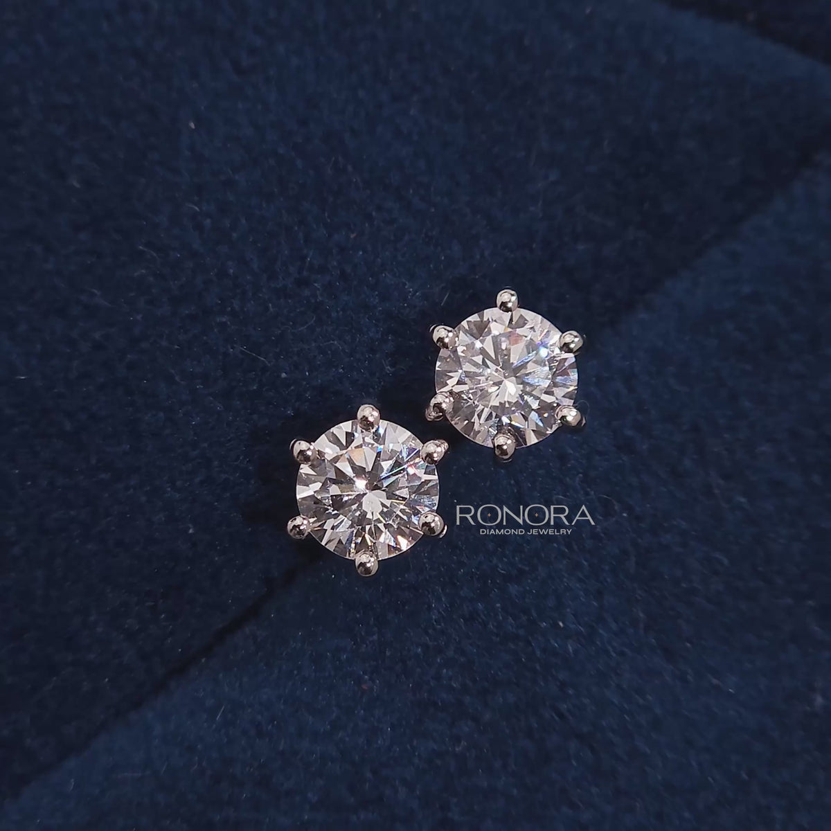 Close-up video of round lab grown diamond stud earrings on blue velvet