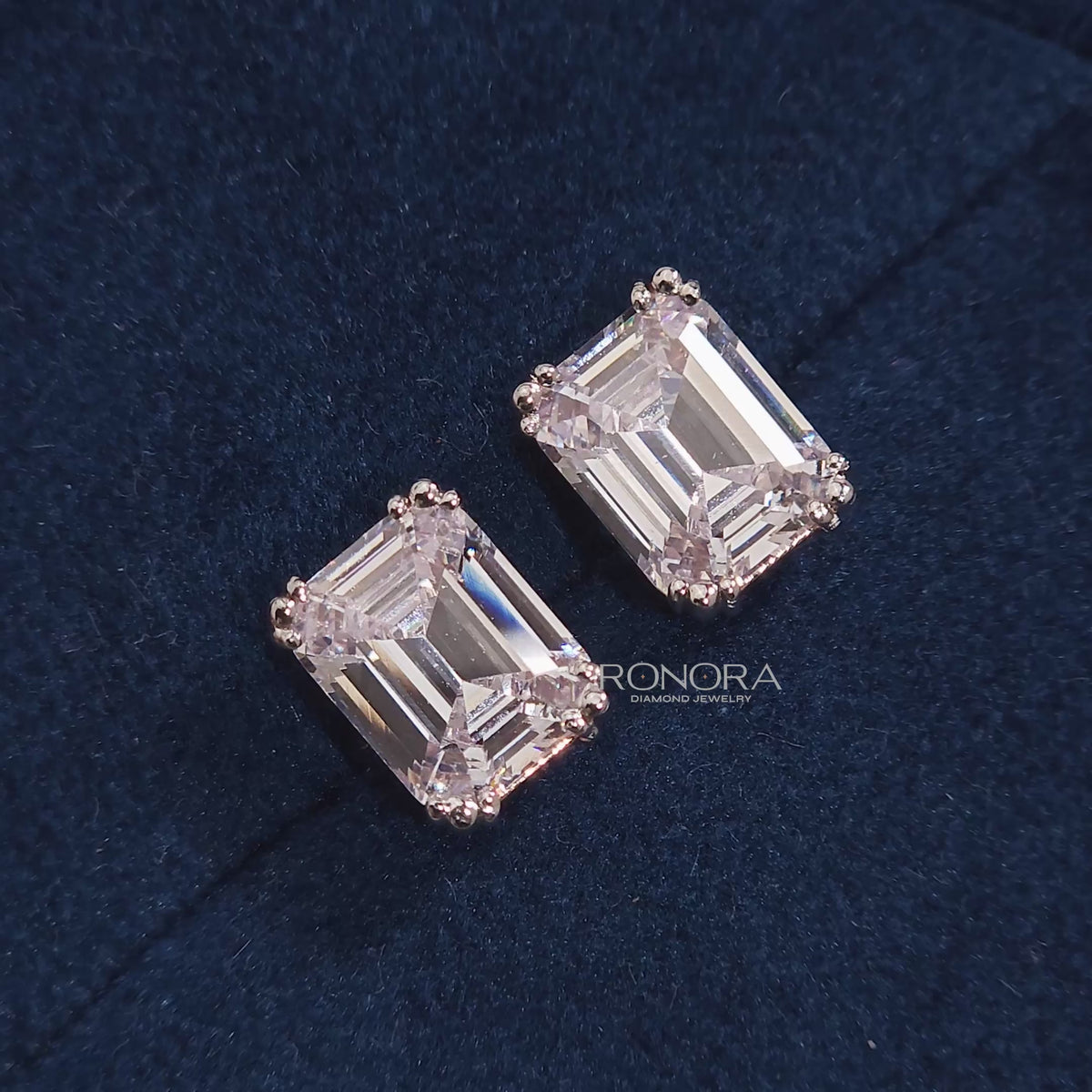 Close-up video of emerald lab grown diamond stud earrings on blue velvet