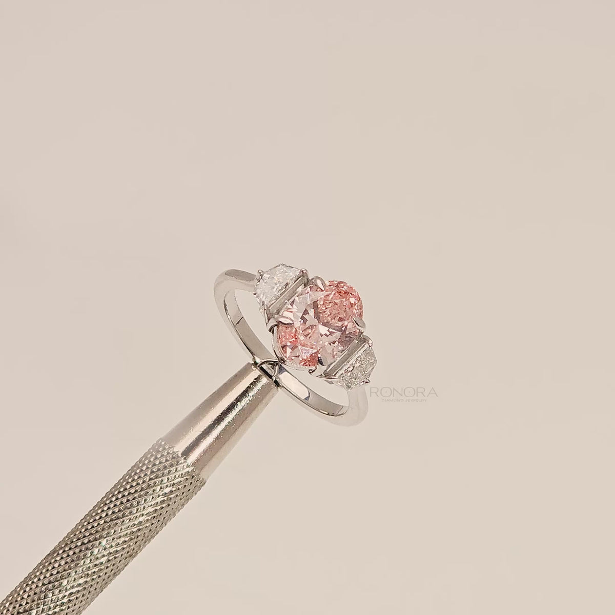 Close-up video of pink lab grown diamond three-stone ring in white metal
