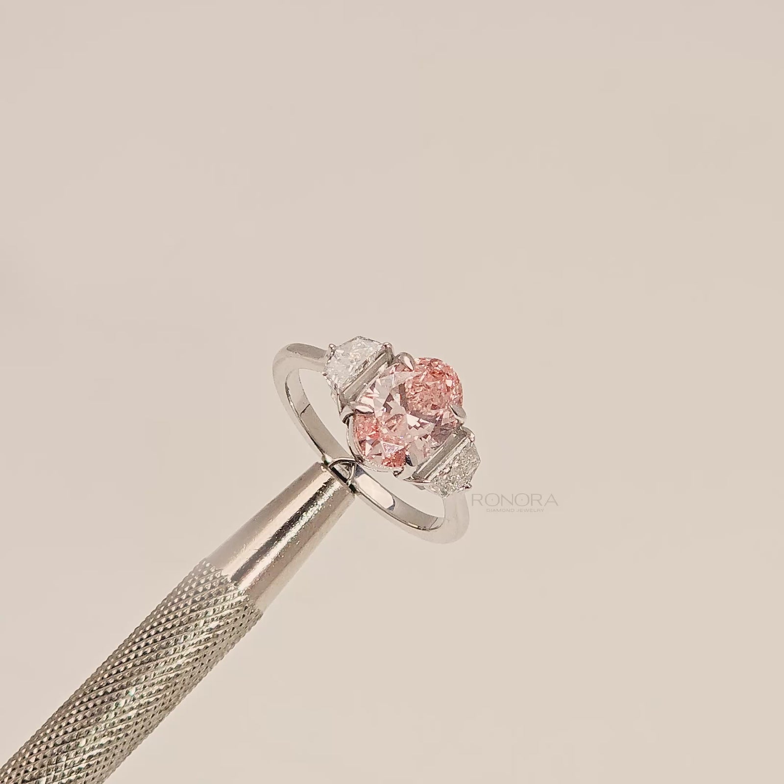 Close-up video of pink lab grown diamond three-stone ring in white metal