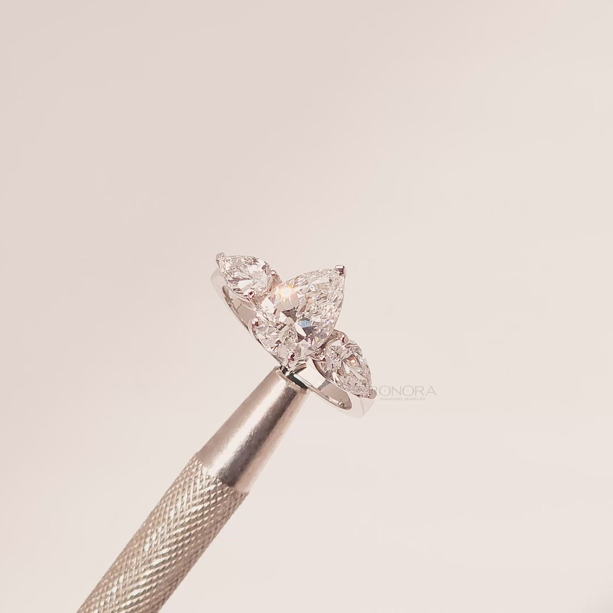 Close-up video of pear lab grown diamond three-stone ring in white metal