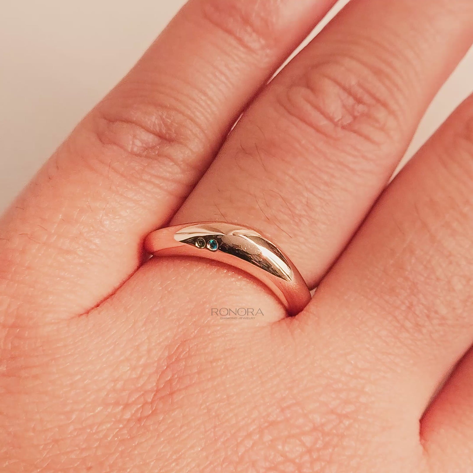 Close-up video of blue accent lab grown diamond curved ring in rose gold
