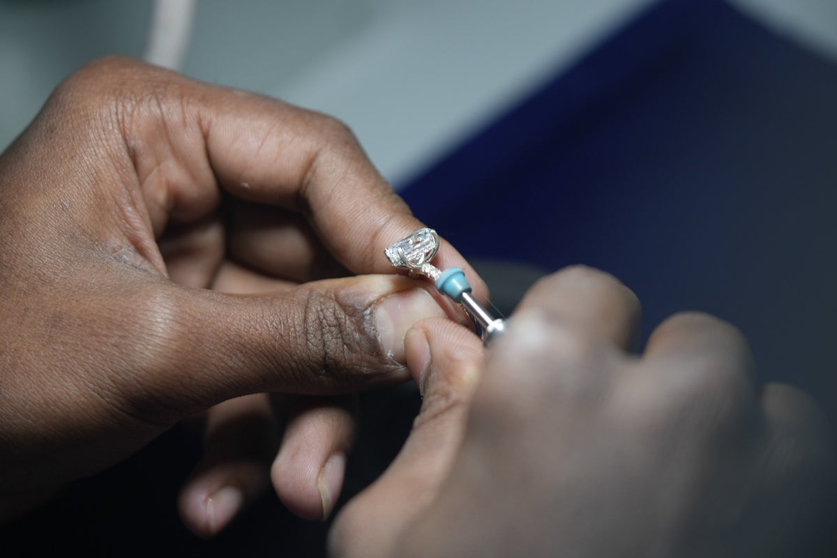 Hands polish the band of a finished ring with a small turquoise rubber wheel