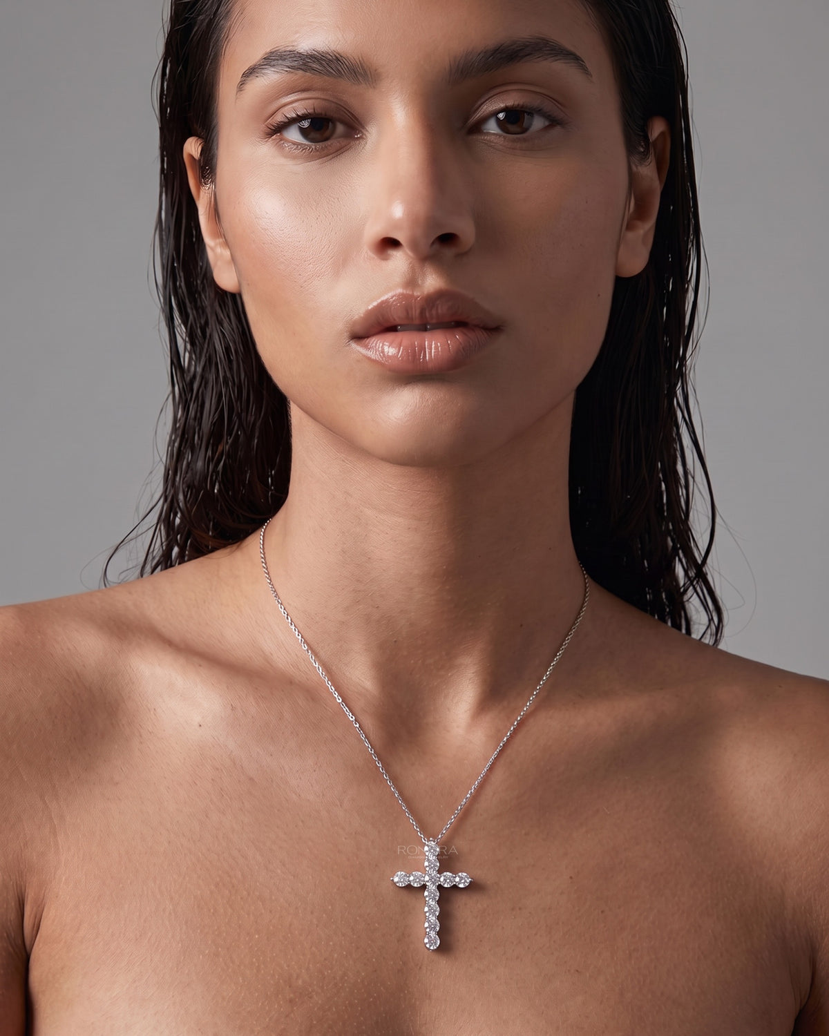 Model with wet-look hair wearing a round lab grown diamond cross necklace on a fine white metal chain