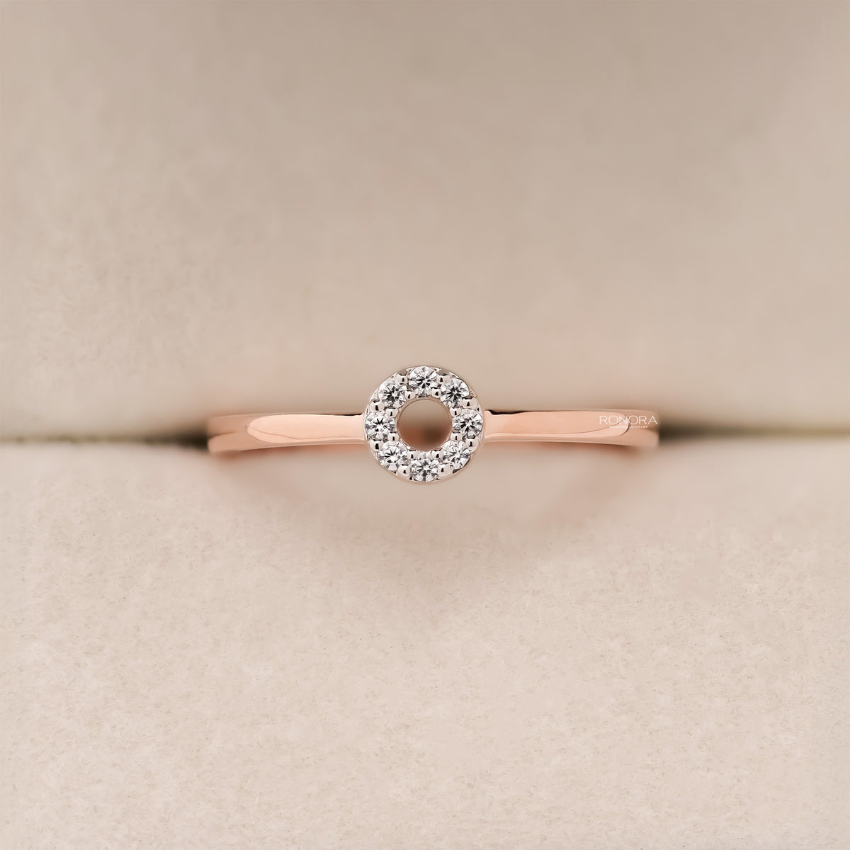 Front close-up of a round lab grown diamond halo ring in rose gold with a small circle of pave stones in a ring box