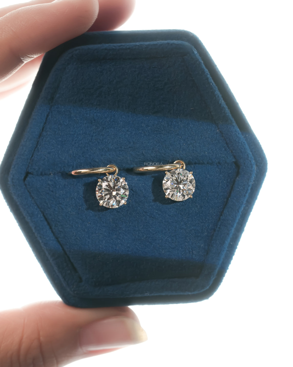 Lab grown diamond huggie drop earrings with round solitaire drops in a hexagonal blue velvet jewelry box