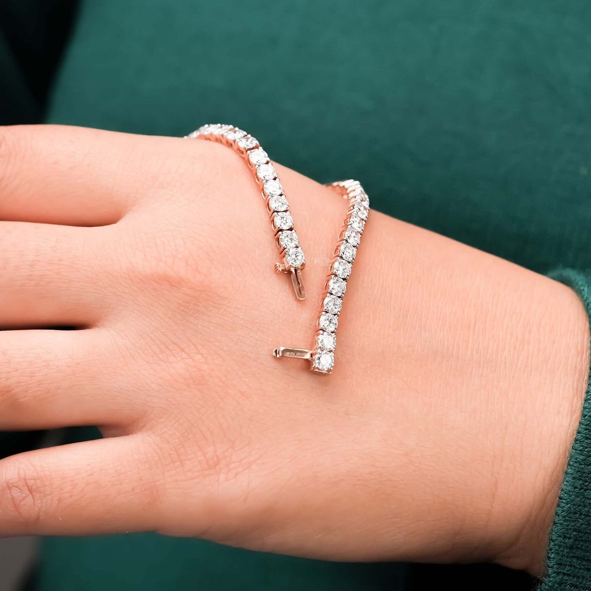 Round lab grown diamond tennis bracelet held above wrist