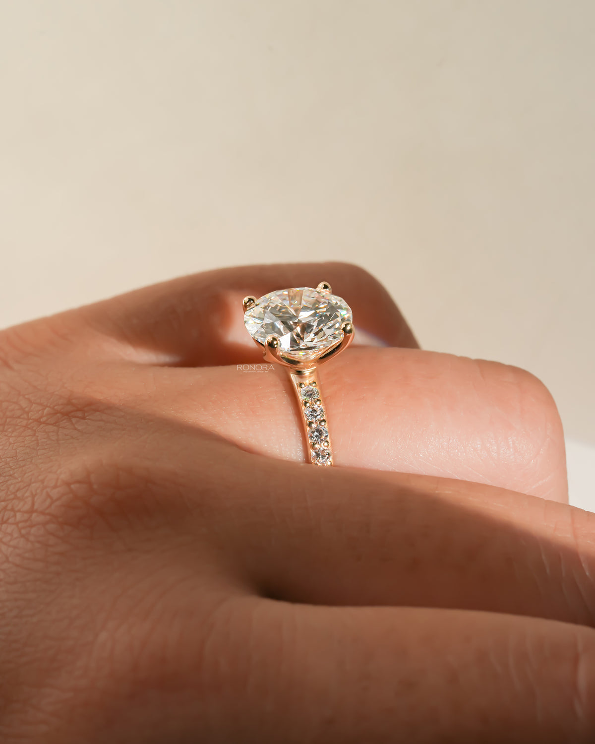 Round pave lab grown diamond engagement ring worn on a hand, side angle showing the stone and pave band