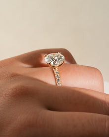 Round pave lab grown diamond engagement ring worn on a hand, side angle showing the stone and pave band