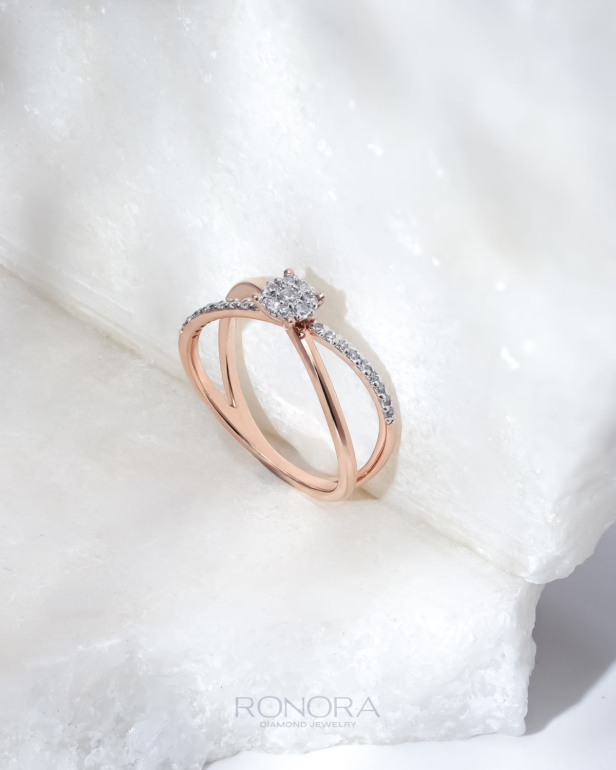 Round split shank lab grown diamond ring in rose gold with pave shoulders, angled view on a white marble block